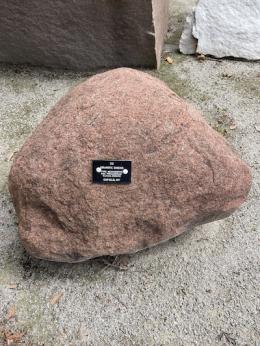 Large pinkish rock with black tag on it.