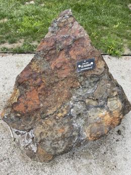 Large Orange and grey pointy rock with a black tag on it.